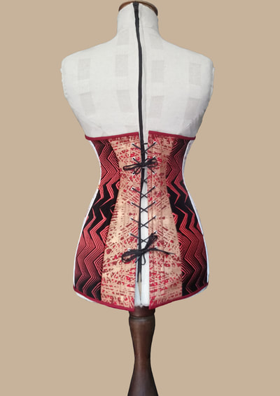 Corset. Back view. Red fine wool screen printed with cross linear pattern in copper, black velvet discharge printed in red zig-zag pattern, red cotton drill, steel split busk, steel spiral/straight boning and rigilene boning, 18 eyelets and black lacing closure.