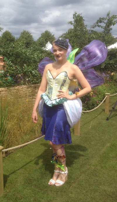 Zoflora competition entry; handmade pansy wings, sublimation print bodice, white shaped rounded skirt and purple printed and gored skirt, fantasy film ankle flower spray and bracelet with paper printed and pleated hat.